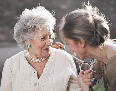 two women holding hands and sharing smiles during conversation
